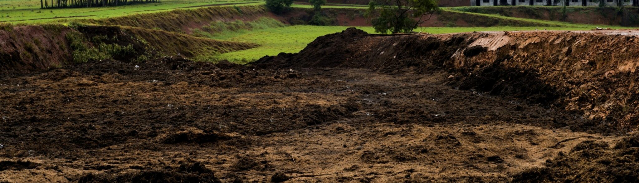large field with piles of rich loamy soil ready to be added for lawns