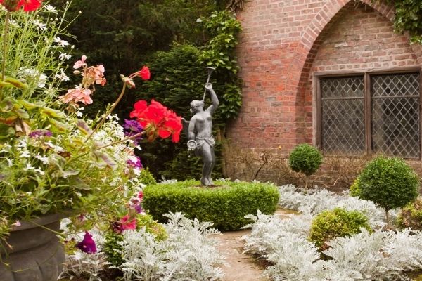 classic statue in center of traditional classic garden with hedges