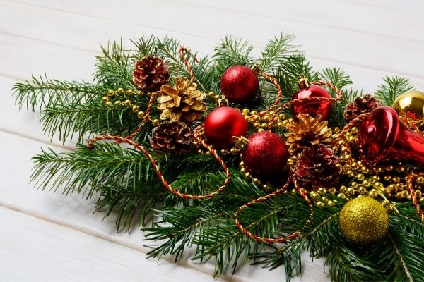 decorated greenery on mantle with red christmas ornaments