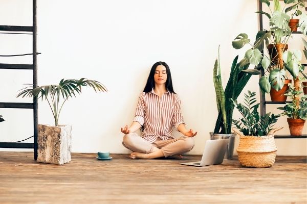 woman meditating by her houseplants