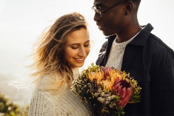 man giving woman flowers in sunlit field language of flowers man giving woman flowers in sunlit field language of flowers