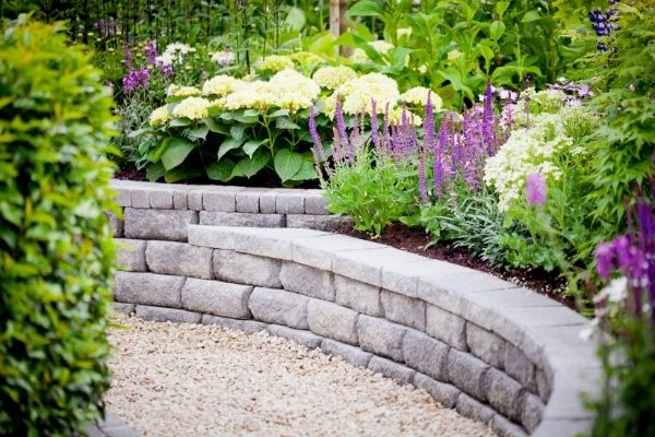 beautiful garden with rock wall of pavers hydrangeas and salvia